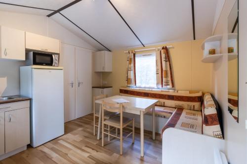 une cuisine et une salle à manger avec une table et des chaises dans l'établissement Mobilhome La Truffière, à Saint-Pompont