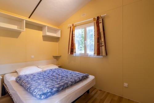 un lit dans une chambre avec une fenêtre dans l'établissement Mobilhome La Truffière, à Saint-Pompont