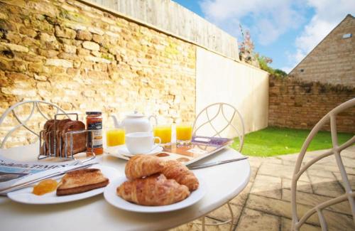 a white table with bread and pastries on it at The Old Bakery Sleeps 4 in Kingham