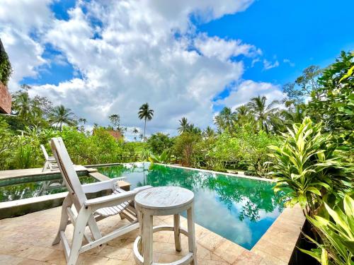a patio with a chair and a table next to a swimming pool at Pondok Is Oke Bamboo Lodge in Licin