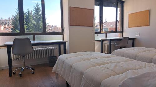 a room with two beds and a desk and windows at Miresileón in León
