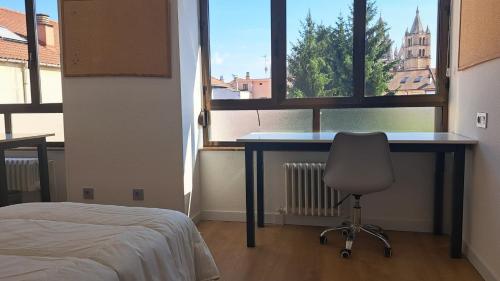 a bedroom with a desk and a chair in front of a window at Miresileón in León