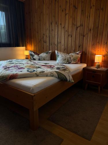 a bed in a room with a wooden wall at Fankhauser Apartments - am Berg in Ried im Zillertal
