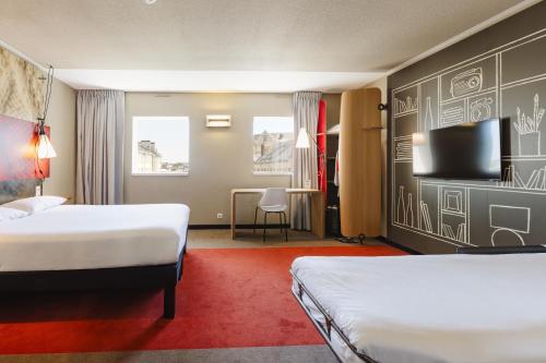 a hotel room with two beds and a flat screen tv at Hotel ibis Rennes Centre Gare Sud in Rennes