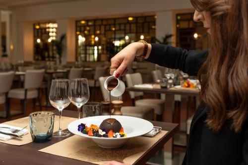 une femme verse du vin dans un bol de nourriture dans l'établissement Occidental Paris Levallois, à Levallois-Perret