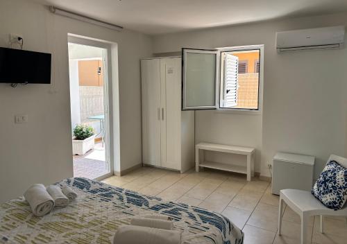 a bedroom with a bed and a tv and a window at Le Torrette Rooms and Apartments in Avola