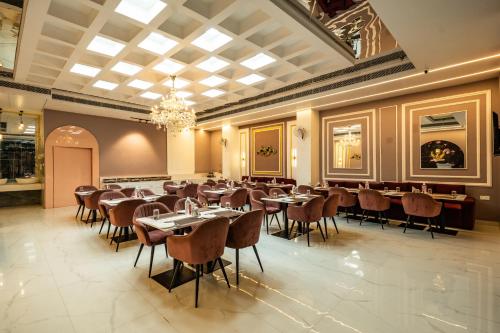 a dining room with tables and chairs and a chandelier at Tripli Hotels Evara Inn in Varanasi