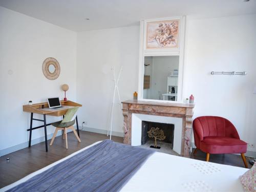 a bedroom with a fireplace and a red chair at La Demeure de Beauvoir - Confort & authenticité in Blois