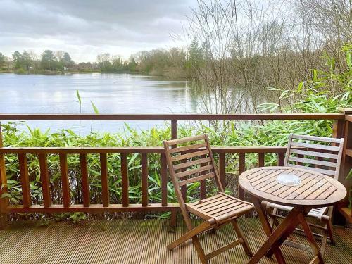 two chairs and a table on a balcony overlooking a river at Holly Lodge 14 Hot Tub in York