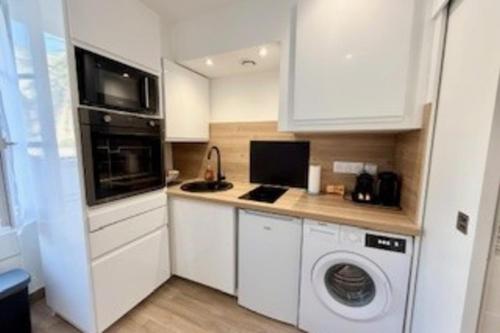 une cuisine avec des armoires blanches et une laveuse et une sécheuse dans l'établissement Luminous cocoon in La Rochelle, à La Rochelle