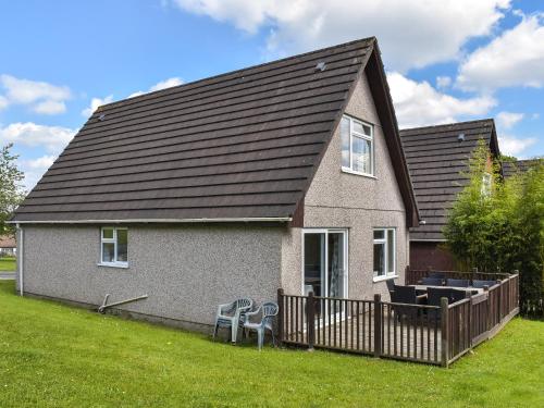 a house with a black roof and two chairs at Honey Lodge in Gunnislake