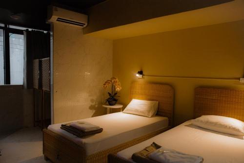 two beds in a room with yellow walls at Metro Pratunam Boutique Hotel in Pratunam