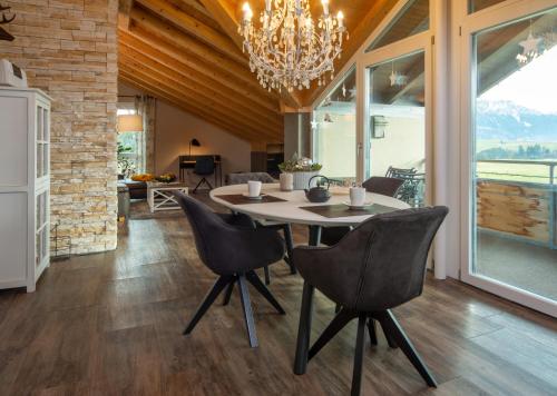 a dining room with a table and chairs and a chandelier at Eldorado - Ferienwohnungen & Suiten in Bolsterlang