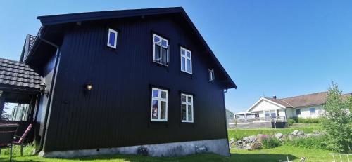 a black house with white windows in a yard at Kylstad Bed and Breakfast in Kylstad