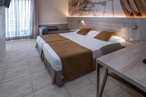 a hotel room with a large bed and a table at GHT Maritim in Calella
