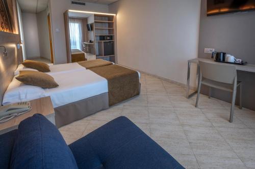 a hotel room with two beds and a desk at GHT Maritim in Calella
