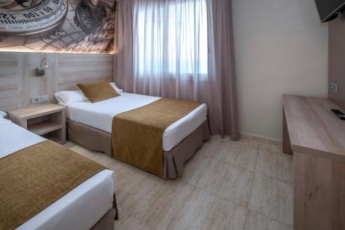 a hotel room with two beds and a desk at GHT Maritim in Calella