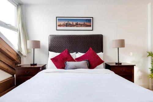 a bedroom with a large white bed with red pillows at Penthouse Loft apartment with roof terrace Not for events or parties in London