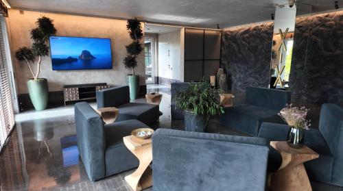 a lobby with blue chairs and a tv on the wall at VAIVA Apartments, Palanga in Šventoji