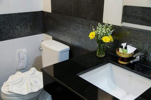 a bathroom with a sink and a toilet with flowers at Noble Boutique Hotel Chiang Mai By J&S Property in Chiang Mai