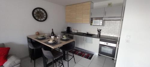 a kitchen with a table and some chairs in it at Le Barbusse LYON-T3-Garage-Terrasse-3 lits-Home Cinema in Pierre-Bénite