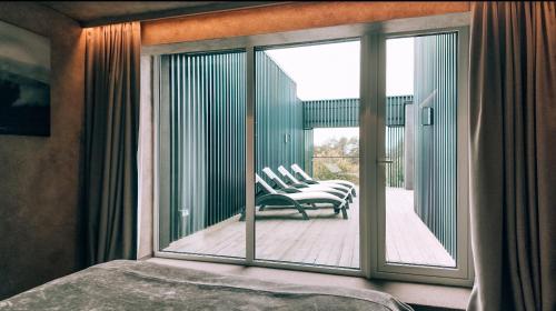 a bedroom with a view of a balcony with chairs at VAIVA Apartments, Palanga in Šventoji