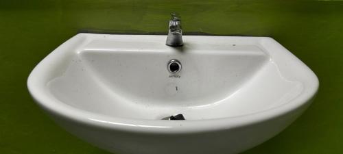 a white sink with a faucet on a green wall at Mapaddegat Surf House in Simpatdegat