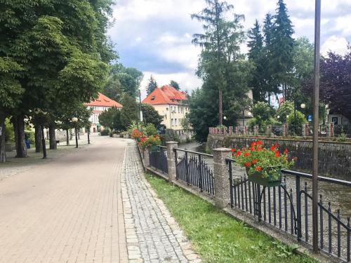 a fence with flowers on it next to a street at Jasny Dwór in Polanica-Zdrój