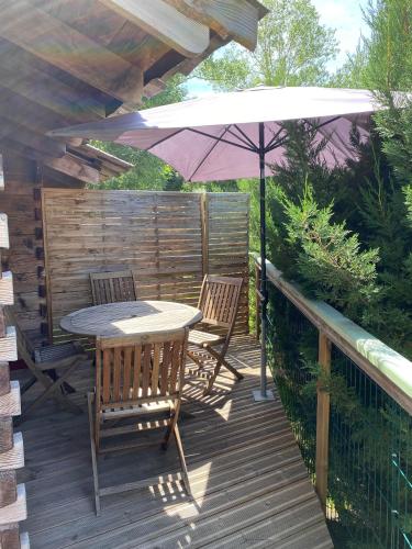 a wooden deck with a table and chairs and an umbrella at Roulottes des Combrailles in Saint-Pardoux