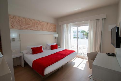 a bedroom with a bed with red sheets and a window at Aequora Lanzarote Suites in Puerto del Carmen
