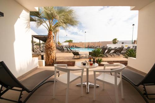 a patio with a table and chairs and a palm tree at Aequora Lanzarote Suites in Puerto del Carmen