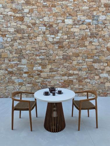 a white table and two chairs and a brick wall at Katokia Kokkina in Finikas