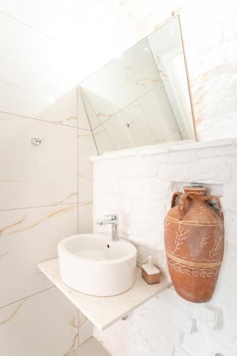 a white bathroom with a sink and a vase at The Stone Nest in Koroni