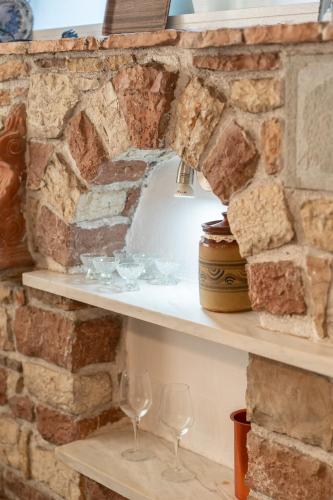 a stone wall with two shelves with wine glasses at The Stone Nest in Koroni