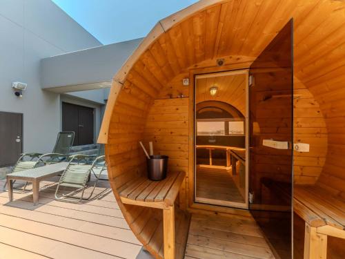 a wooden sauna with a bench and chairs on a deck at HOTEL felice Osaka -伊丹空港- in Toyonaka