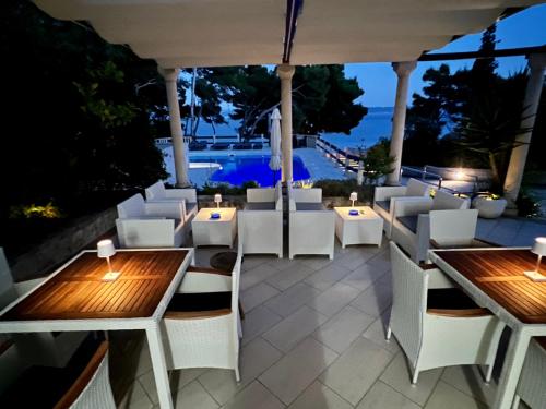 a restaurant with white chairs and tables and a view of the ocean at Vila Vera Seafront Apartments in Sumartin