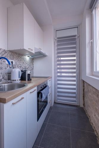 a kitchen with white cabinets and a sink and a window at 086 Studio Apartment in Cetinje