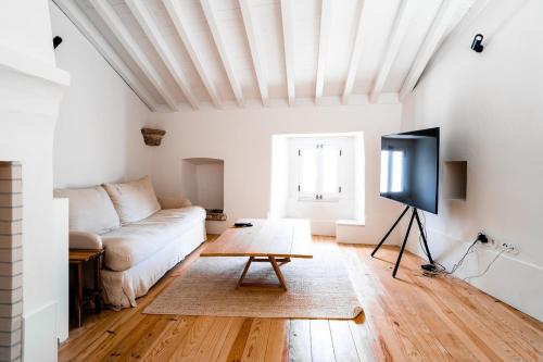 a living room with a couch and a tv at Fonte da Vila House in Castelo de Vide