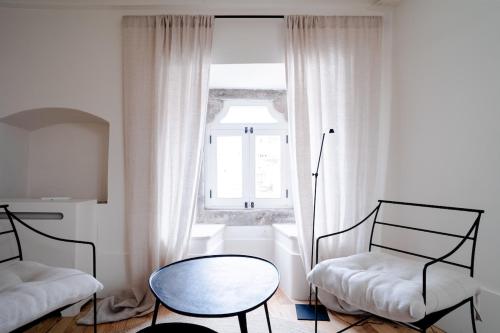 sala de estar con 2 sillas, mesa y ventana en Fonte da Vila House, en Castelo de Vide