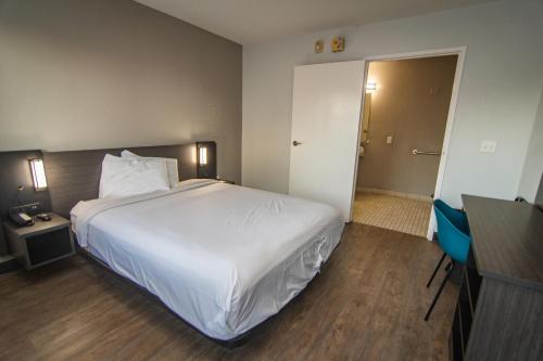 a bedroom with a large white bed and a desk at Motel 6-Lakeland, FL in Lakeland