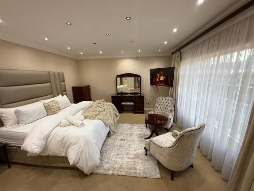 a bedroom with a bed and a chair and a mirror at Elegant 5BR House with Pool, Gourmet Kitchen and Reliable Generator in Johannesburg