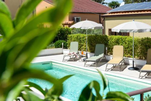 a pool with chairs and umbrellas next to a house at Villa Margherita in Cefalù