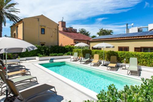 a pool with chairs and umbrellas next to a house at Villa Margherita in Cefalù