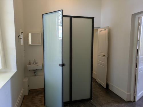a bathroom with a glass door and a sink at La Lampisterie - Converted railway workshop on the edge of the Voie Verte in Saint-Gengoux-le-National