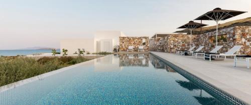 a swimming pool with chairs and the ocean in the background at TWWO Antiparos in Antiparos