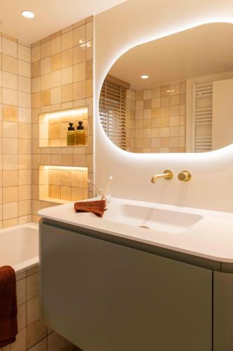 a bathroom with a sink and a mirror and a tub at ElloStays in Middelkerke