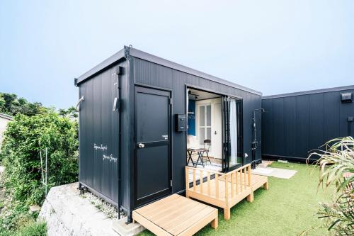 a black shipping container house with a deck at T-Base 01 in Tateyama