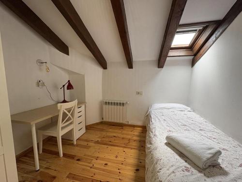 a bedroom with a bed and a desk and a window at BPirineos-La Montañeta in Benasque