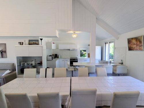 une salle à manger et une cuisine avec une table et des chaises blanches dans l'établissement Maison moderne 8 personnes, jardin, parkings, fibre THD, plage 5 min, à Vannes