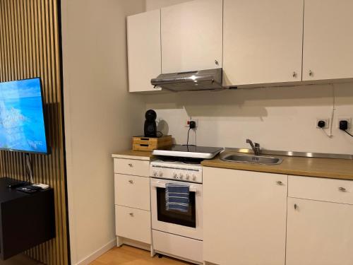 a kitchen with white cabinets and a stove and a sink at Bentley Floriana Suites in Il-Furjana